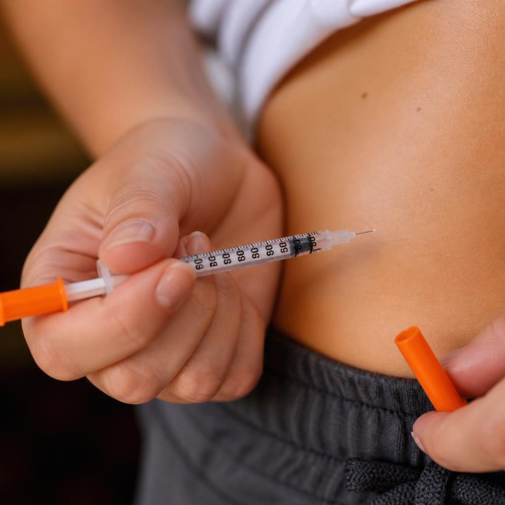 Close-up of hands holding a marked syringe near the midsection